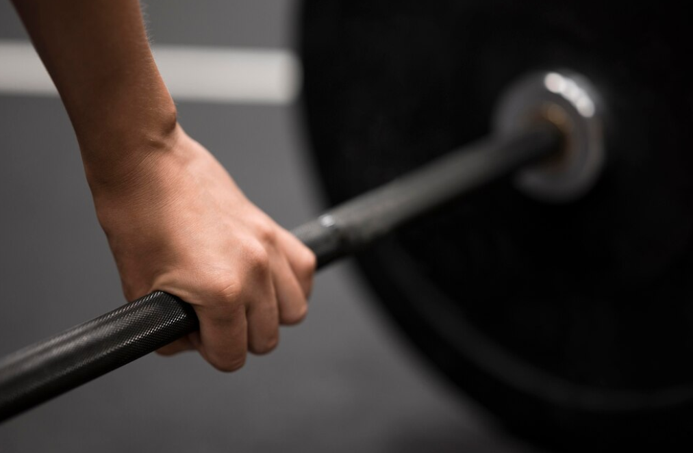 a close up view hand holding  a barbell in the gym