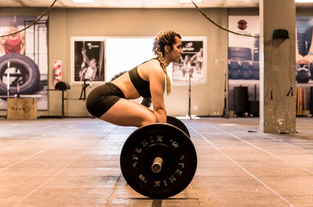 A woman preparing to lift a barbell in a weightlifting area