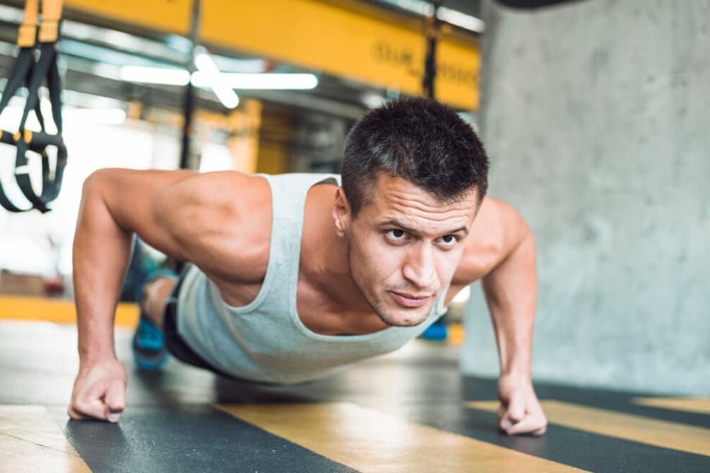 A focused man does knuckle push-ups in a gym
