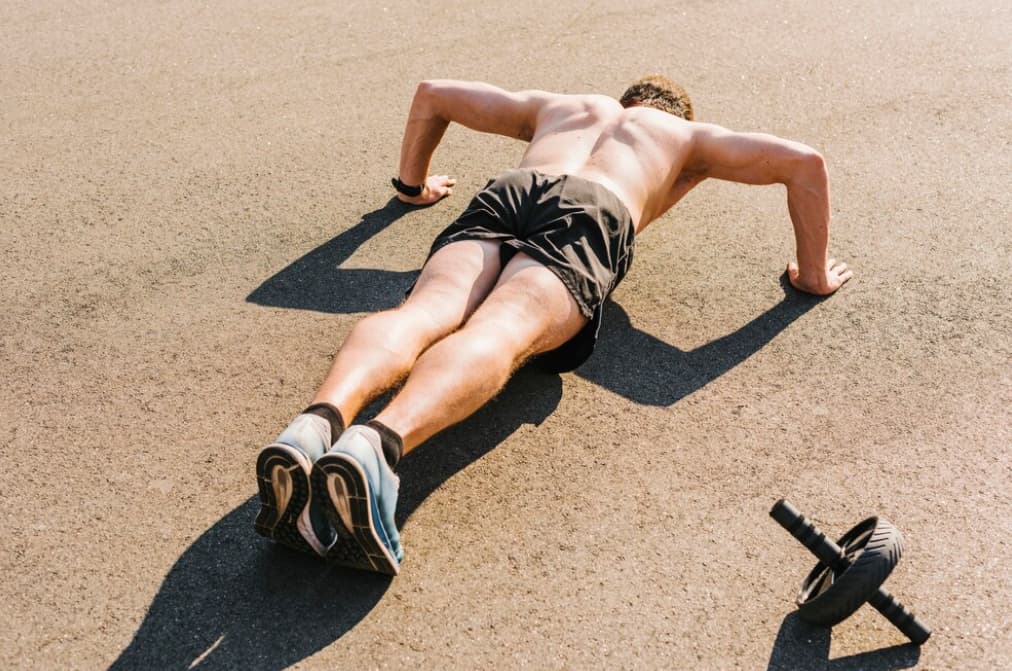 An athlete does push-ups beside push-up wheels outside