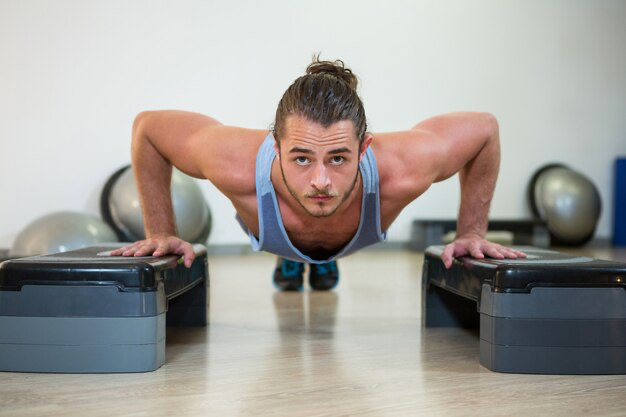 A man does push-ups on stands and looks forward